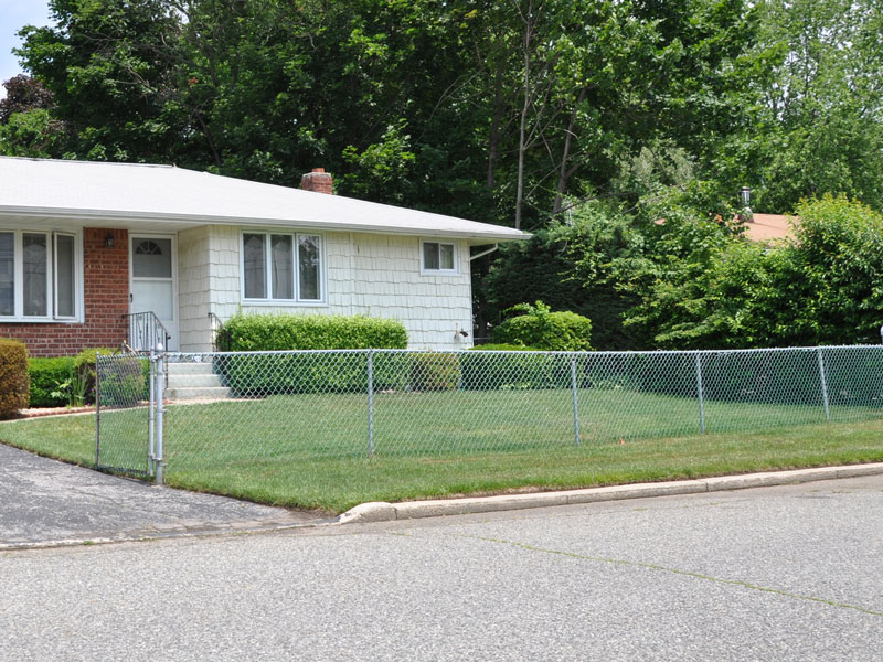 chain link fence in front yard of white and red brick house