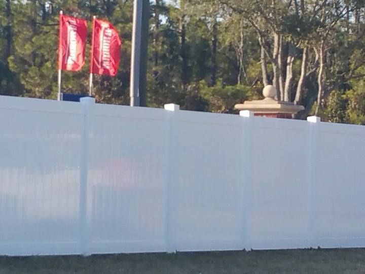 white vinyl fence in front of red flags